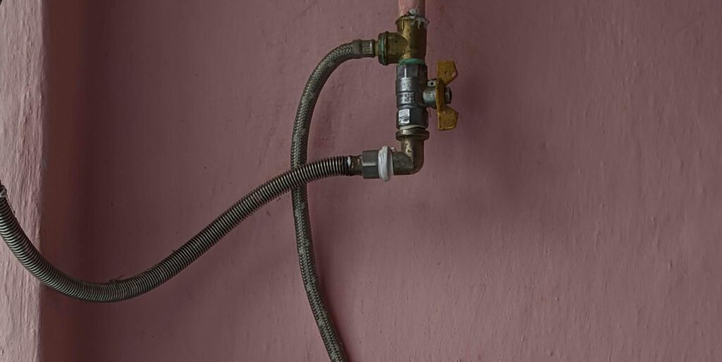 A floral design kettle on a retro stove against a pink wall, showcasing vintage kitchen style.