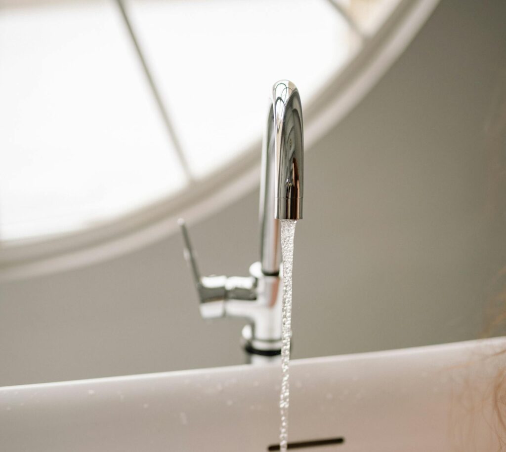 A serene bathtub filled with bubbles and flowing water from a chrome faucet indoors.