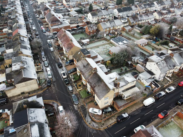 Snow-covered suburban neighborhood with cars and houses under winter conditions.